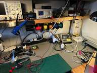 a desk with a computer, a laptop, and a bunch of wires